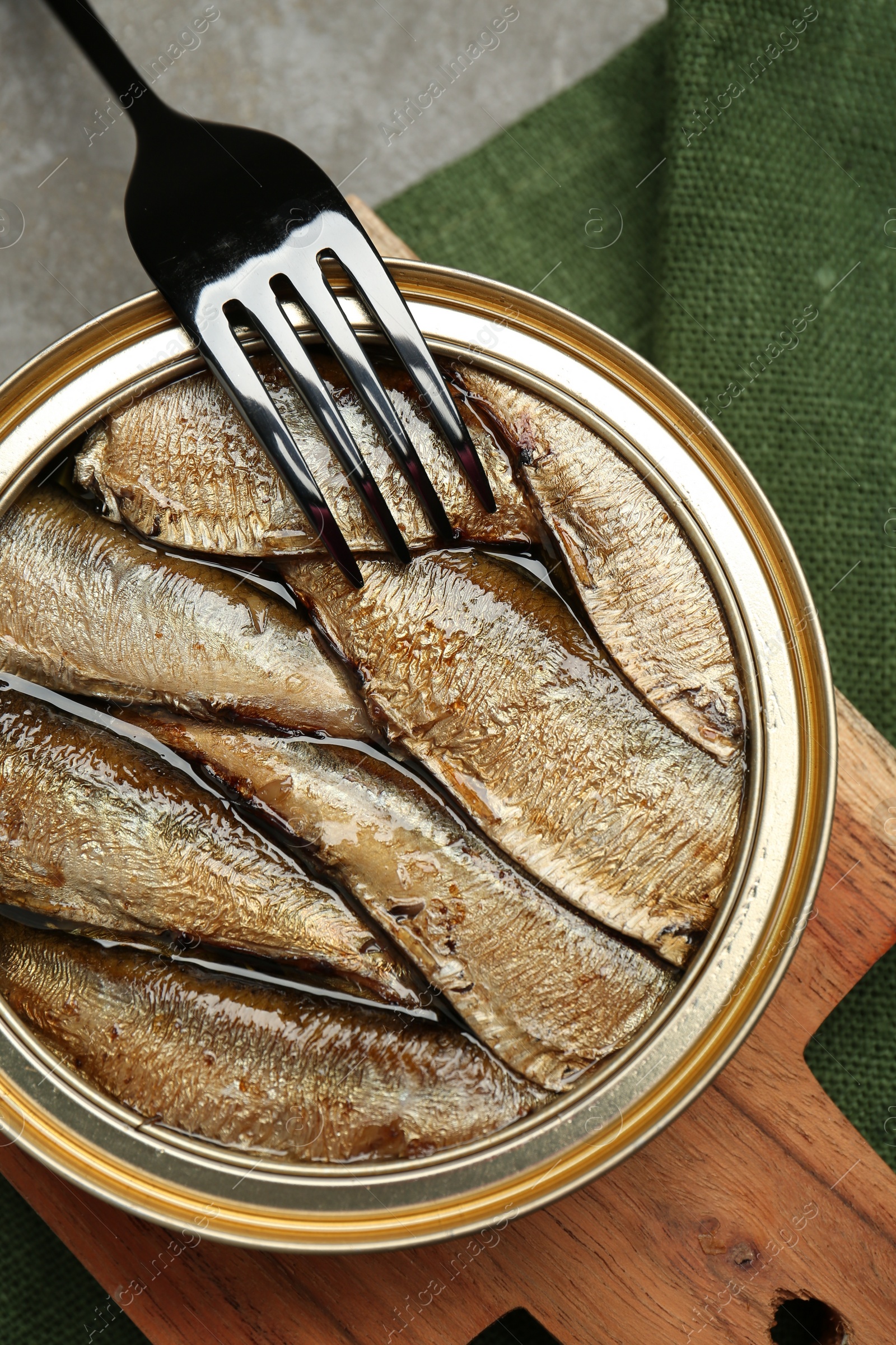 Photo of Canned sprats and fork on grey table, top view