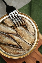 Canned sprats and fork on grey table, top view