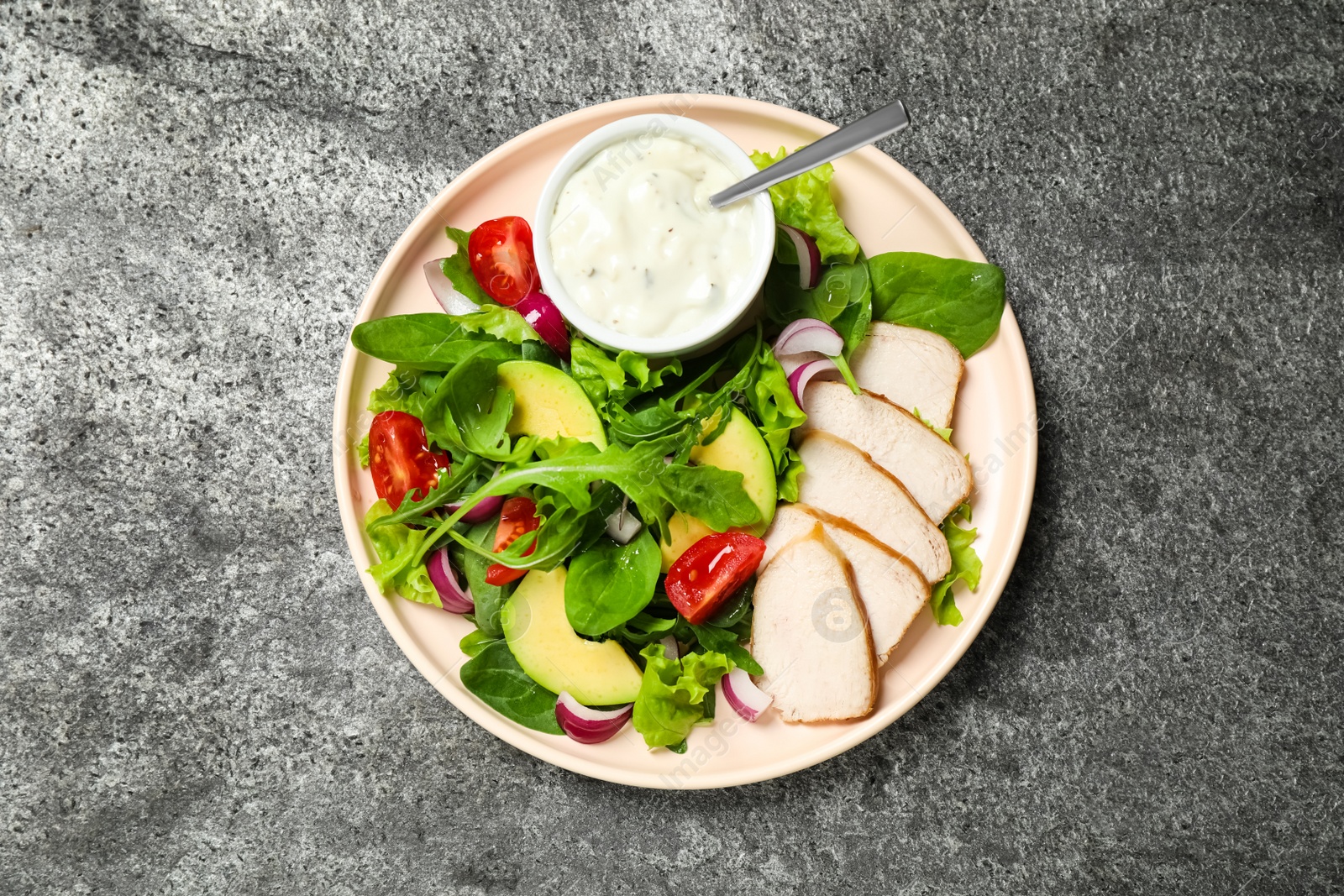 Photo of Delicious salad with chicken, arugula and avocado on grey table, top view