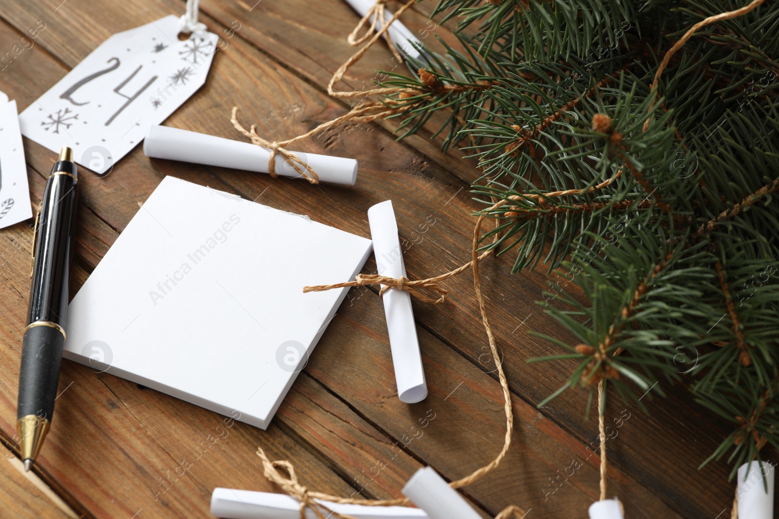 Photo of Paper notes and fir tree on wooden table, closeup. Creating advent calendar