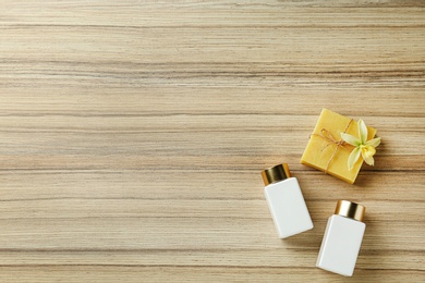 Photo of Cosmetic bottles and handmade soap on wooden table, flat lay with space for text. Spa treatment