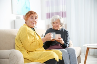 Elderly women drinking tea together in living room