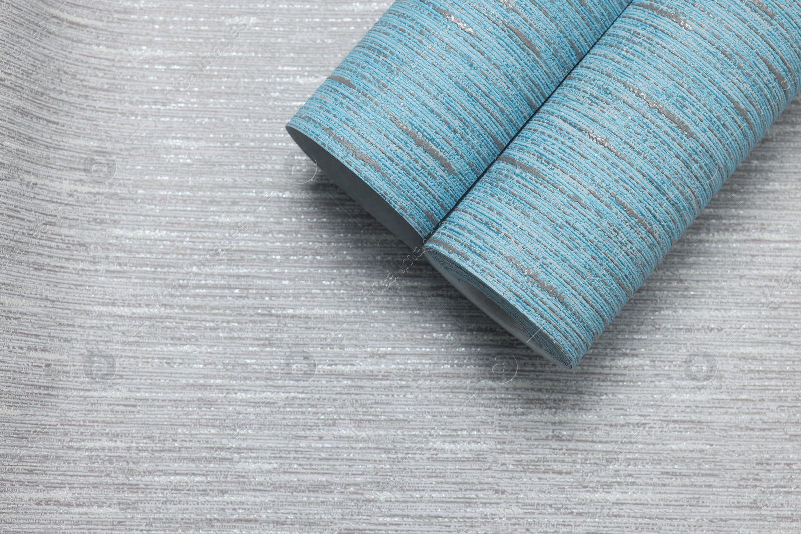 Photo of Light blue wallpaper roll on grey sample, top view. Space for text