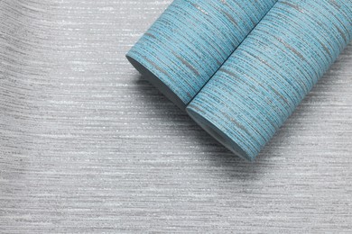 Photo of Light blue wallpaper roll on grey sample, top view. Space for text