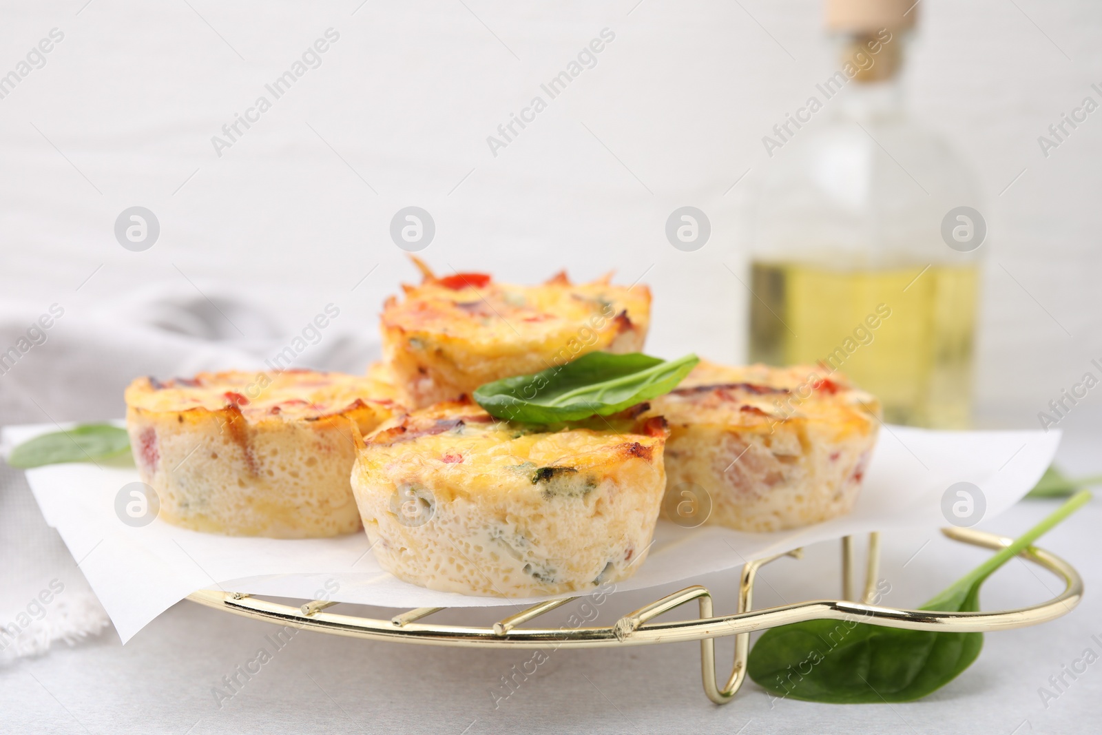 Photo of Freshly baked bacon and egg muffins with cheese on light gray table, closeup. Space for text