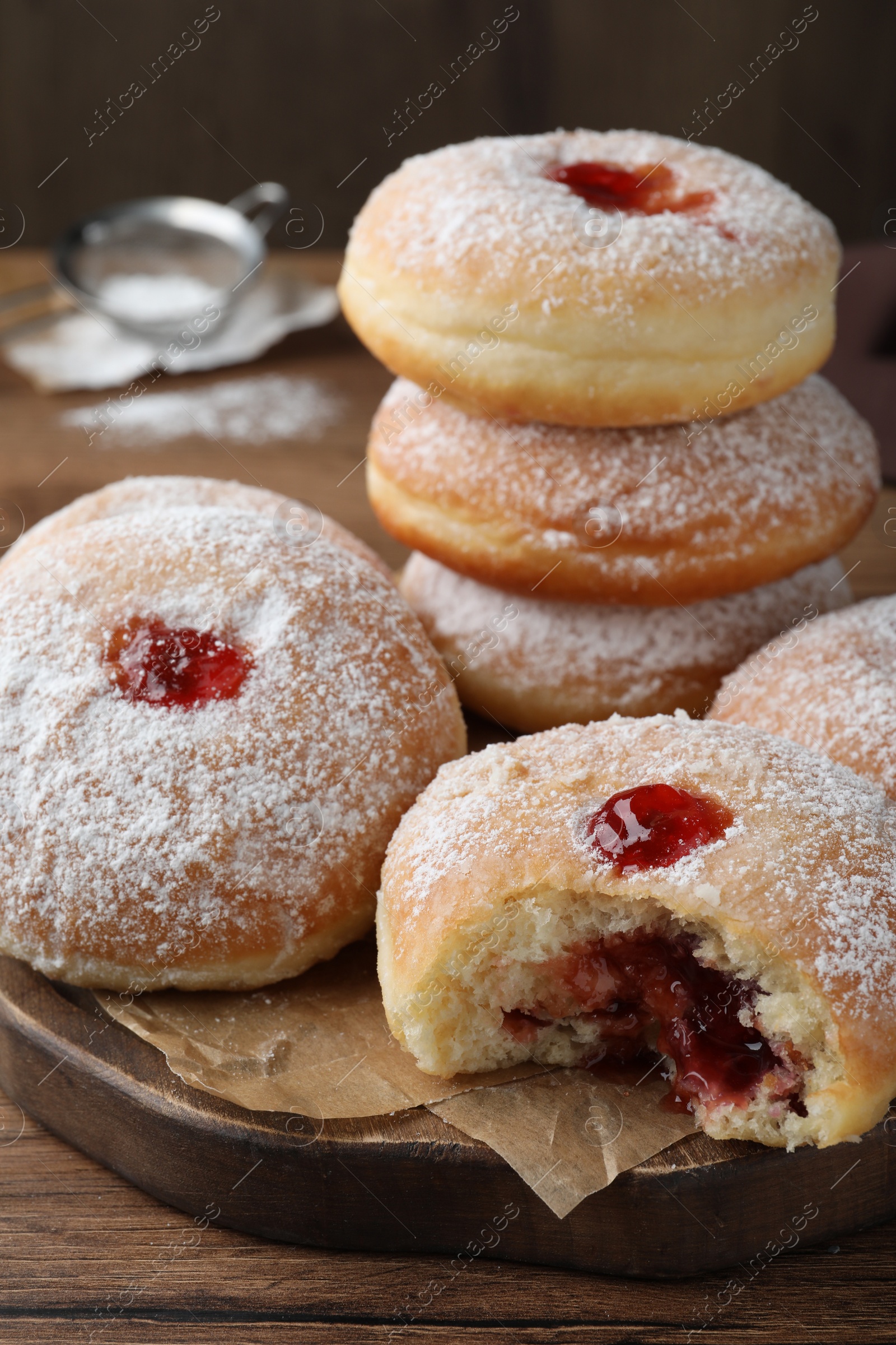 Photo of Delicious donuts with jelly and powdered sugar on wooden board, closeup