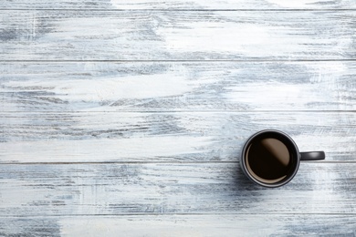 Photo of Ceramic cup with hot aromatic coffee on wooden background, top view