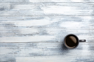 Ceramic cup with hot aromatic coffee on wooden background, top view