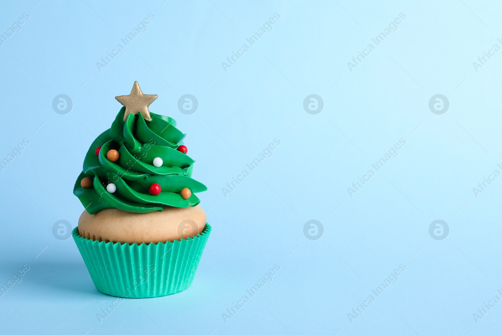 Photo of Christmas tree shaped cupcake on light blue background. Space for text