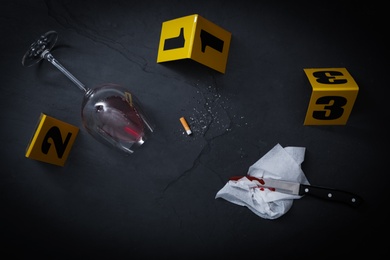 Flat lay composition with evidences and crime scene markers on black background