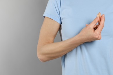 Photo of Woman snapping her fingers on light grey background, closeup and space for text. Bad habit