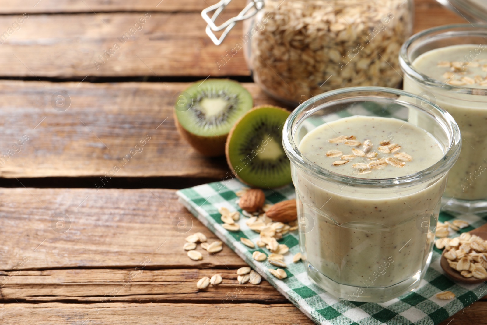 Photo of Tasty kiwi smoothie with oatmeal on wooden table, space for text