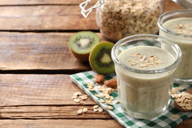 Photo of Tasty kiwi smoothie with oatmeal on wooden table, space for text