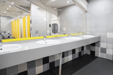 Public toilet interior with sinks, mirror and colorful tiles