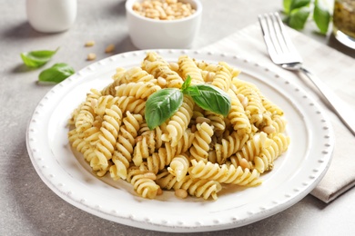 Plate with delicious basil pesto pasta on table