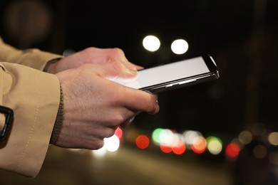 Photo of Man using smartphone on night city street, closeup