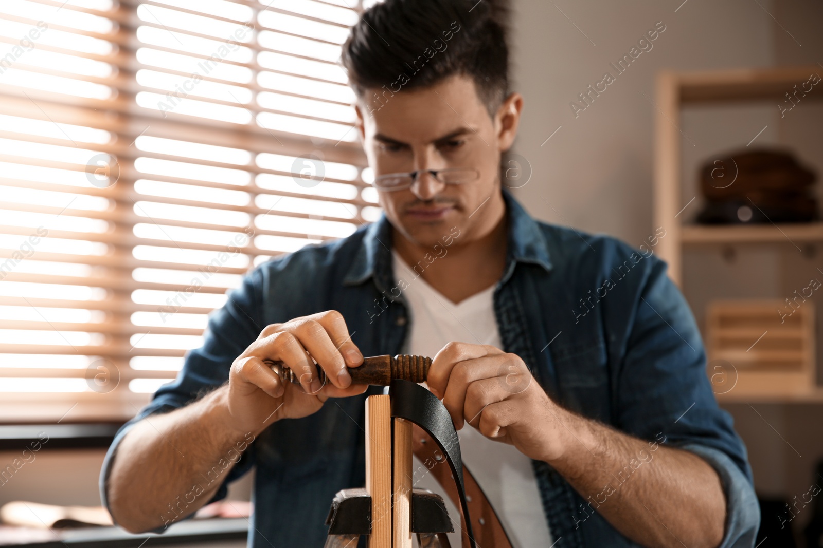 Photo of Man burnishing edges of leather belt in workshop