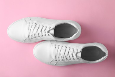 Photo of Pair of stylish white sneakers on pink background, top view