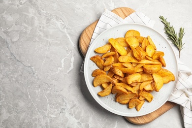 Photo of Plate of delicious oven baked potatoes on marble background, top view. Space for text