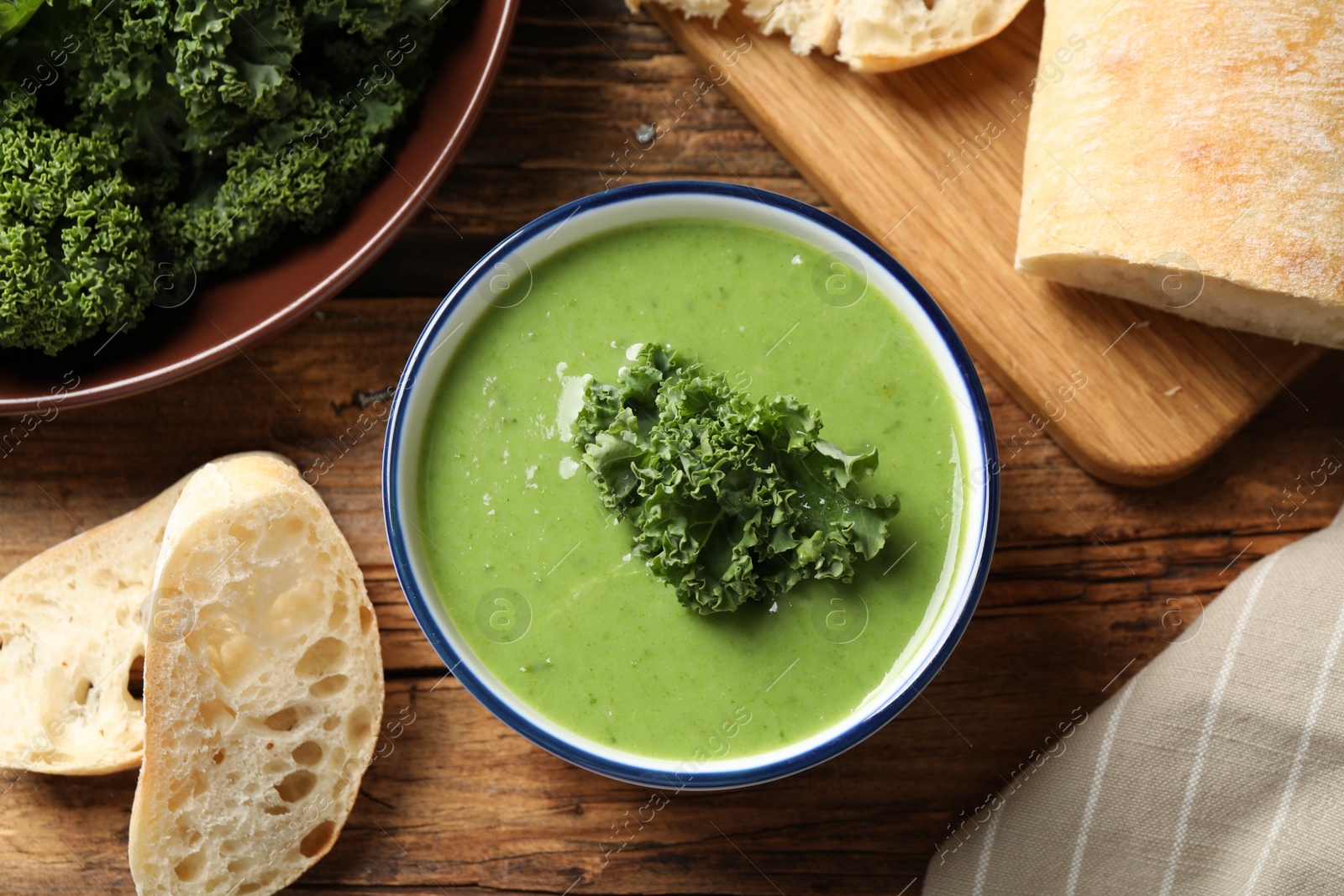 Photo of Tasty kale soup on wooden table, flat lay