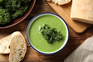 Photo of Tasty kale soup on wooden table, flat lay