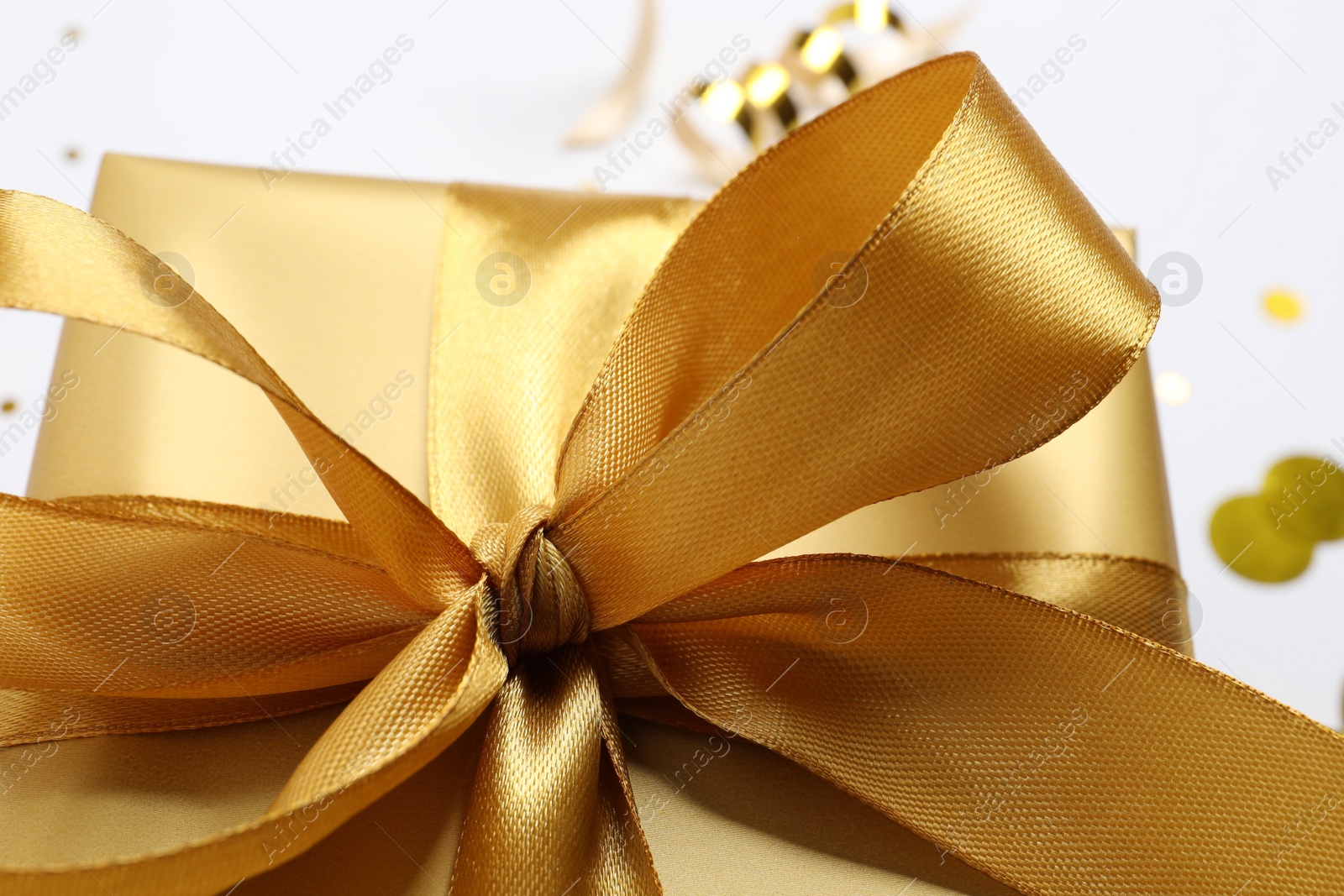 Photo of Beautiful golden gift box with bow on white background, closeup
