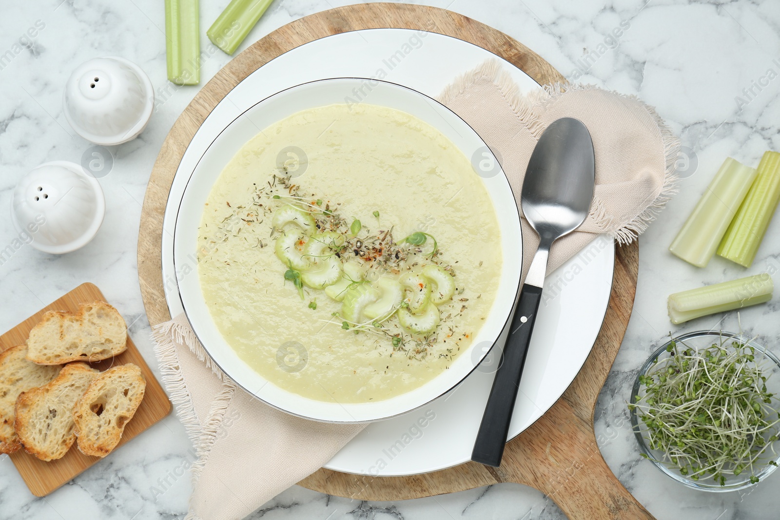 Photo of Delicious celery soup served on white marble table, flat lay