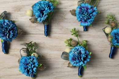 Photo of Stylish blue boutonnieres on white wooden table, flat lay
