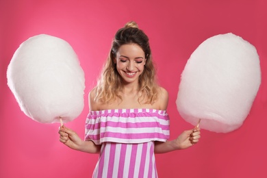 Portrait of pretty young woman with cotton candy on pink background