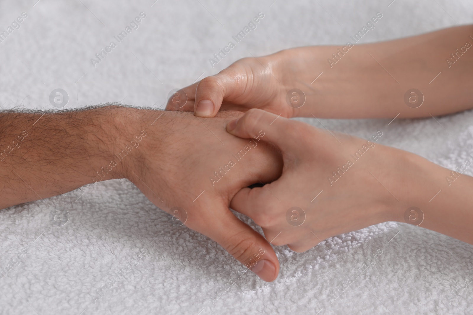 Photo of Man receiving hand massage on soft towel, closeup