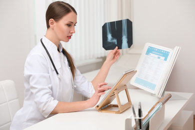 Orthopedist examining X-ray picture at desk in clinic