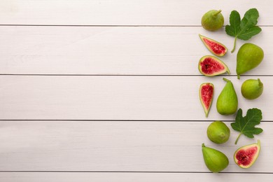 Cut and whole green figs with leaves on white wooden table, flat lay. Space for text