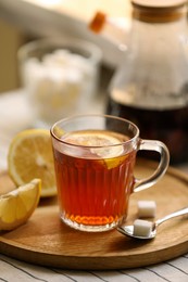 Photo of Glass mug of aromatic tea with lemon and sugar on table, closeup