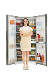 Young woman near open refrigerator on white background