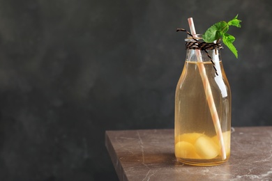 Photo of Bottle with tasty melon ball drink on table against dark background. Space for text