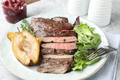 Photo of Delicious roasted beef meat, caramelized pear and greens served on light table, closeup
