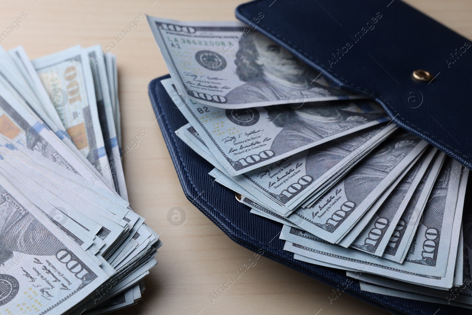 Photo of Dollar banknotes and wallet on wooden table, closeup. Money exchange