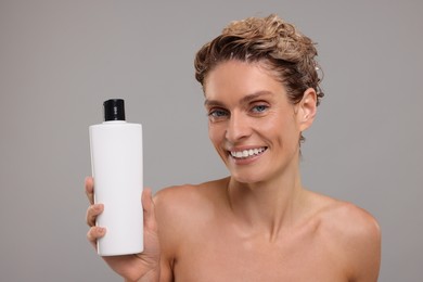 Photo of Washing hair. Portrait of beautiful happy woman with bottle on light grey background