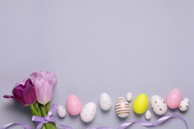 Flat lay composition with festively decorated Easter eggs on grey background. Space for text