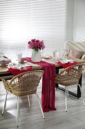 Photo of Pink peonies on table with beautiful setting and rattan chairs in dining room