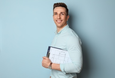 Male real estate agent with clipboard on light background