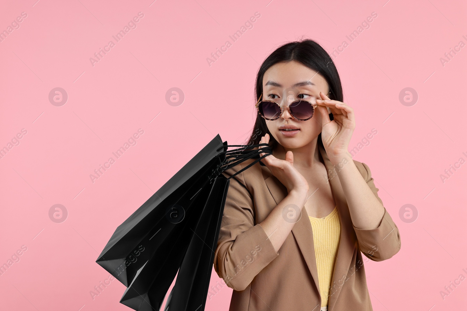 Photo of Beautiful woman with shopping bags on pink background. Space for text