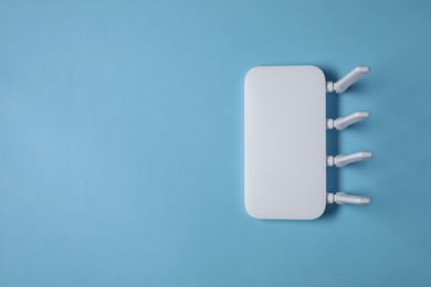 New white Wi-Fi router on light blue background, top view. Space for text