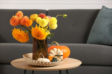 Photo of Beautiful autumn bouquet and pumpkins on coffee table near sofa in room