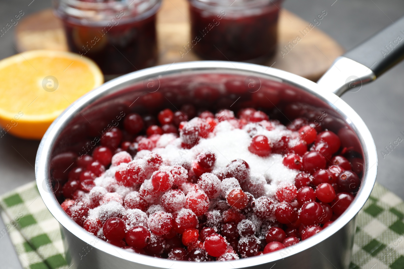 Photo of Making cranberry sauce. Fresh cranberries with sugar in saucepan on table, closeup