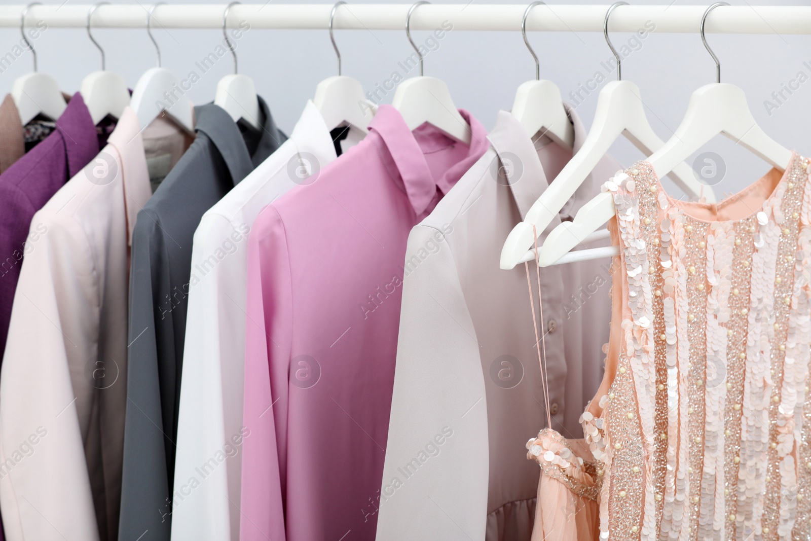 Photo of Rack with stylish clothes on light background, closeup