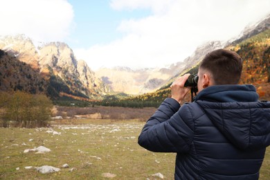 Photo of Boy looking through binoculars in beautiful mountains, back view. Space for text