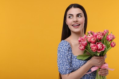 Happy young woman with beautiful bouquet on orange background. Space for text