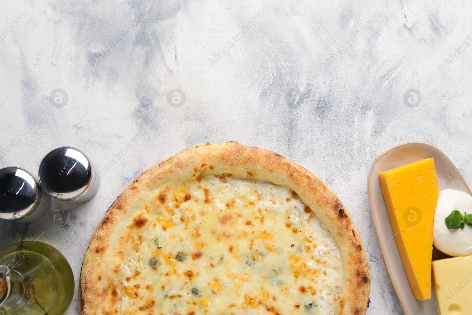 Photo of Delicious cheese pizza, oil and different kinds of cheese on light grey textured table, flat lay. Space for text