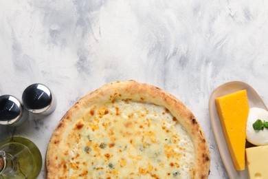 Photo of Delicious cheese pizza, oil and different kinds of cheese on light grey textured table, flat lay. Space for text